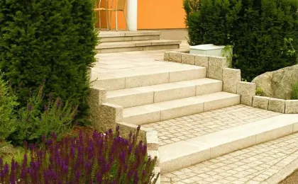 Eine elegant gestaltete Außentreppe aus hellem Naturstein führt zum Hauseingang. Edle Natursteinarbeiten im Vorgarten.