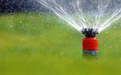 Ein moderner Versenkregner sprüht feines Wasser auf eine grüne Rasenfläche. Effiziente Gartenbewässerung im Einsatz.