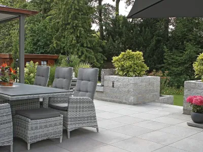 Großzügige Terrasse ausgelegt mit modernen keramischen Platten und stilvollen Gartenmöbeln.