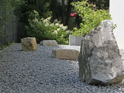 Ein breit angelegtes Kiesbeet mit großen Findlingen aus Naturstein und dekorativer Bepflanzung.