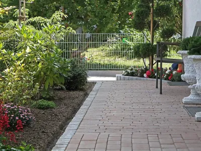 Gepflasterter Gartenweg aus Beton-Verbundpflaster flankiert von einem reich blühenden Beet.