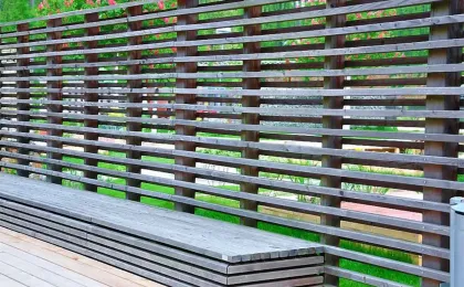 Ein moderner Sichtschutz aus horizontalen Holzlamellen schützt eine Terrasse. Stilvolle Zäune für mehr Privatsphäre.