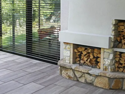Gemütliche Outdoor-Feuerstelle aus robustem Naturstein auf einer modern gepflasterten Terrasse.