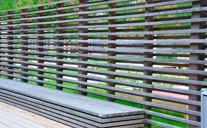 Ein moderner Sichtschutz aus horizontalen Holzlamellen schützt eine Terrasse. Stilvolle Zäune für mehr Privatsphäre.