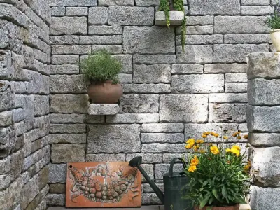 Eine idyllische Grillecke umgeben von rustikalen Mauern aus echtem Naturstein im Garten.
