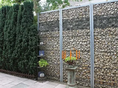 Stabile Gabionenwand befüllt mit Naturstein als moderner Sichtschutz im Rahmen der Gartengestaltung.