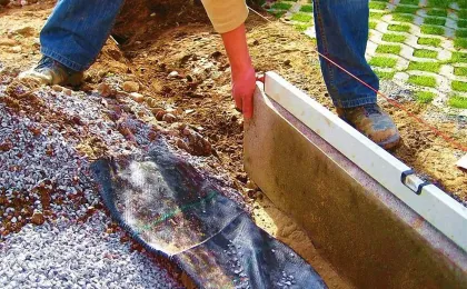 Handwerker richtet eine Kante mit der Wasserwaage aus. Stabile Einfassung für Pflastersteine bei Pflasterarbeiten.