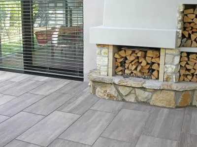 Moderne Terrasse mit langlebigen Keramikplatten in warmer Holzoptik neben einer Feuerstelle.