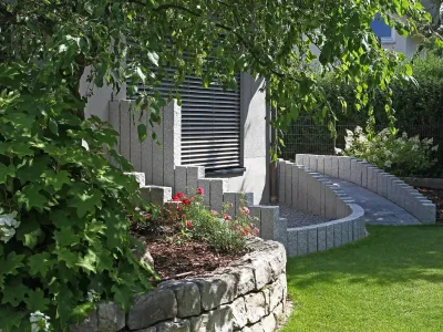 Moderne Gartengestaltung mit einer Mauer aus Naturstein und geschwungenen Elementen.