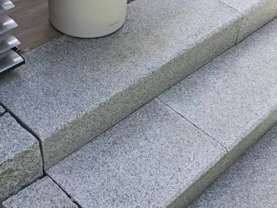 Trittsichere Blockstufen aus geflammtem Naturstein führen elegant auf eine erhöht liegende Terrasse.
