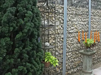 Moderne Gabionen gefüllt mit hellem Naturstein dienen als langlebiger Sichtschutz im Garten.