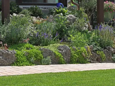 Kreative Gartengestaltung & Gartenpflege: Ein üppig bepflanzter Steingarten mit massivem Naturstein.